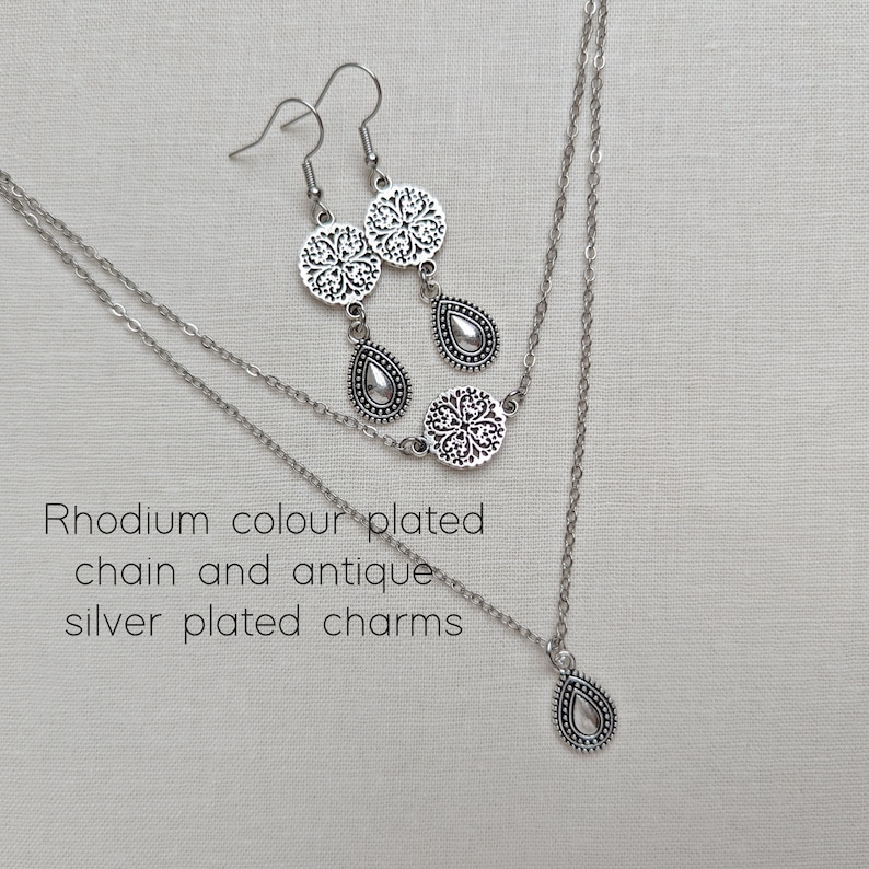 Top view of a rhodium colour plated double strand necklace with two different types of antique silver plated charms on each chain.