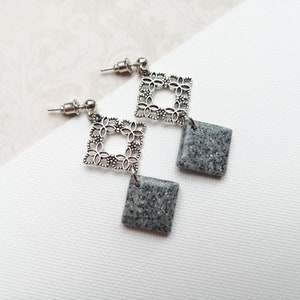 May include: A pair of silver filigree earrings with gray glitter square dangles.