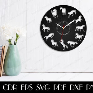 May include: A black clock face with white horse silhouettes around the edge. The clock hands are red and white. The clock is on a white wall with a vase of white flowers and a stack of books.