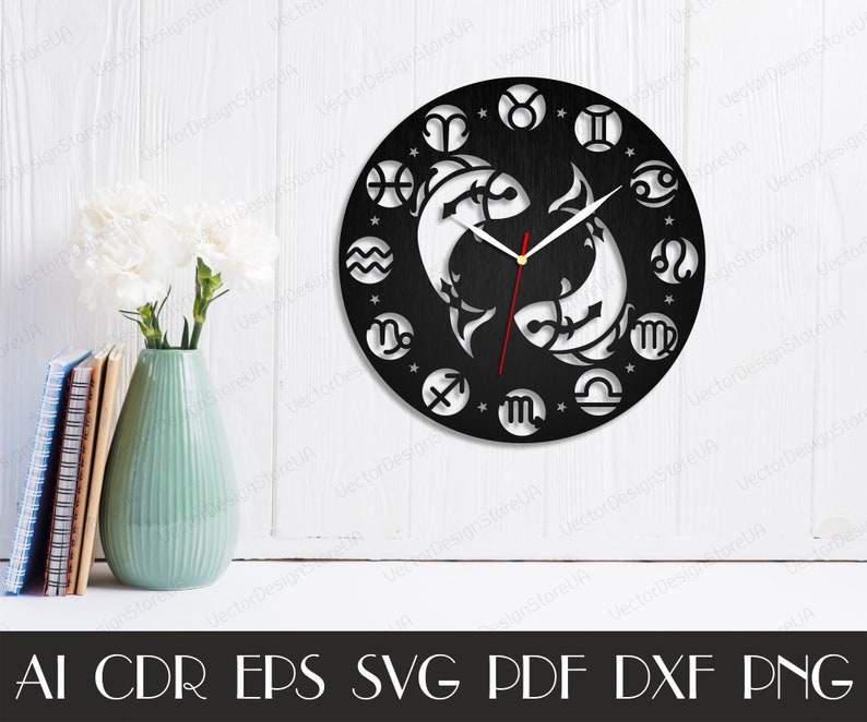 May include: Black and white clock with a circular design featuring the astrological signs of the zodiac. The clock face is made of wood and has a black background. The clock hands are red and white. The clock is surrounded by a white border.