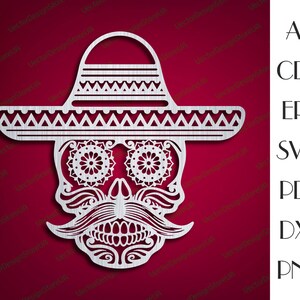 May include: A white, detailed, paper cut-out design of a skull wearing a sombrero. The skull has a mustache and a floral design around the eyes.