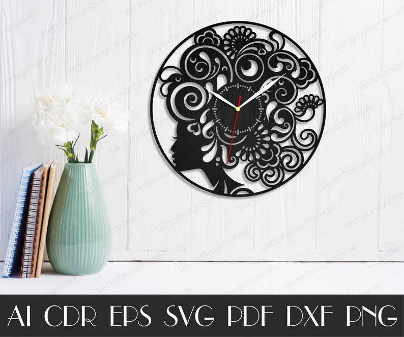 Puede incluir: Reloj en blanco y negro con una silueta de rostro de mujer y dise&ntilde;os florales intrincados. La esfera del reloj es redonda y tiene un fondo negro con manecillas blancas.