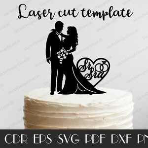 Op de afbeelding: Zwarte silhouet van een bruid en bruidegom met een hartvormige topper waarop 'Mr & Mrs' staat met twee ringen. De topper staat op een witte bruidstaart.