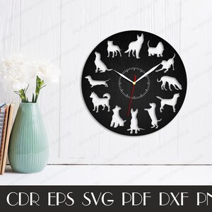 Peut inclure: Un cadran d'horloge noir avec des silhouettes de chiens blanches autour des aiguilles de l'horloge. Le cadran d'horloge est sur un mur blanc avec un vase de fleurs blanches et une pile de livres sur une &eacute;tag&egrave;re.