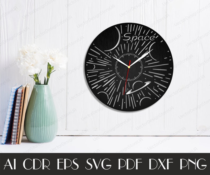 May include: A black wooden clock with a white space-themed design. The clock face features a stylized sun with rays, planets, and stars. The clock hands are red and silver. The clock face also includes the word "Space".