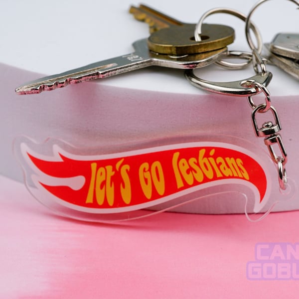 May include: A clear acrylic keychain with a red and yellow flame design. The keychain reads "let's go lesbians" in yellow text. Several keys are attached to the keychain.