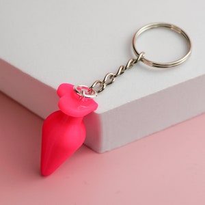May include: A pink heart-shaped keychain with a silver chain and ring.