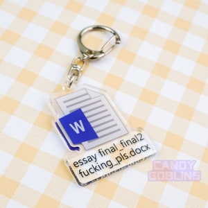 Puede incluir: Un llavero de acr&iacute;lico transparente con forma de documento de Microsoft Word con el texto "essay final_final2 fucking_pls.docx" en &eacute;l. El llavero tiene un anillo de metal plateado.