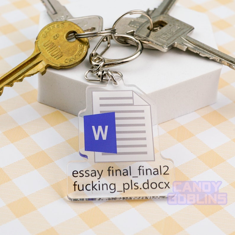 Puede incluir: Un llavero de acr&iacute;lico transparente con un icono de documento de Microsoft Word y el texto "essay final_final2 fucking_pls.docx". El llavero est&aacute; unido a un juego de llaves.