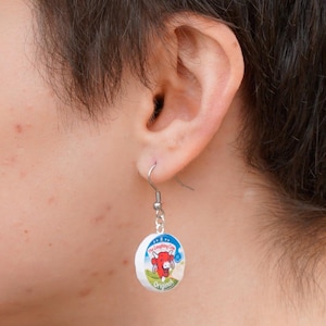 A person wears a Laughing Cow earring
