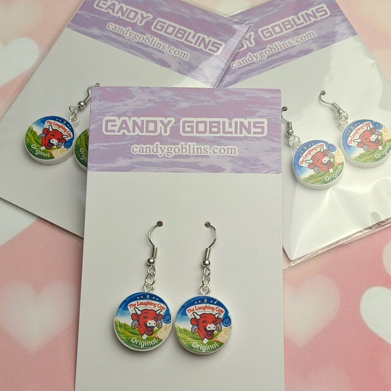 Three packets of Candy Goblins Laughing Cow earrings are packaged up and on display