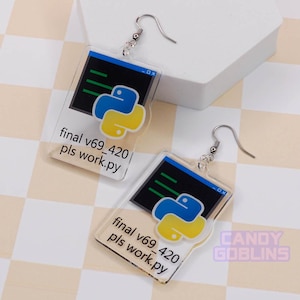 Pode incluir: Um par de brincos de acrílico transparente com um logotipo Python azul e amarelo e o texto "final v69_420 pls work.py" em cada brinco.