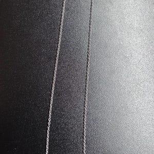 Op de afbeelding: Een zilveren ketting met een hanger met een gestileerde figuur en de letters "&Delta;&Sigma;&Theta;".
