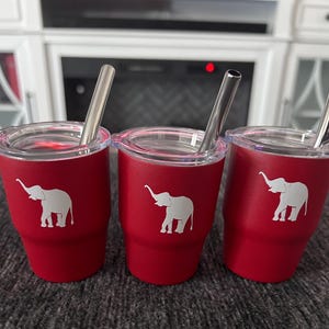 May include: Three red insulated tumblers with clear lids and stainless steel straws. Each tumbler features a white elephant graphic.