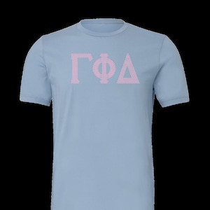 May include: A light blue t-shirt with a pink Greek letter design that reads "ΓΦΔ".
