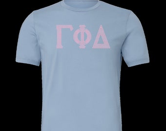 Op de afbeelding: Een lichtblauw T-shirt met een roze Grieks letterontwerp dat "ΓΦΔ" luidt.