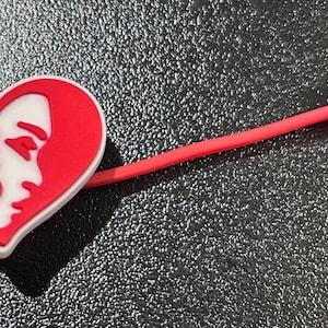 May include: A red heart-shaped charm with a white silhouette of a face and the letters "1913" and "&Delta;&Sigma;&Theta;" inside. The charm is attached to a red string.