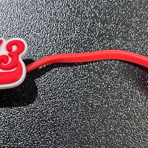 May include: Red rubber cable tie with a red and white 1913 logo. The logo is in a white and red baseball style font.