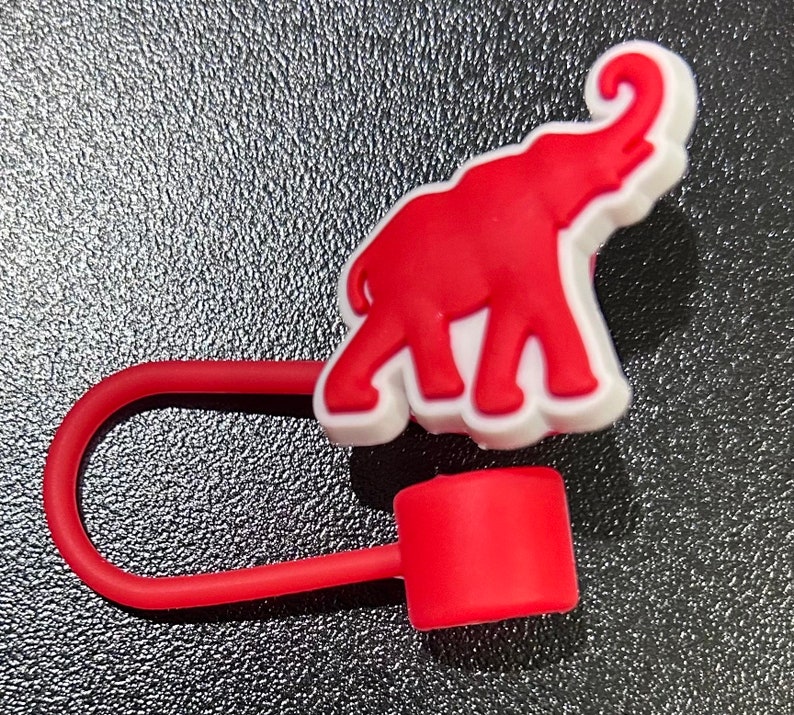 May include: Red rubber elephant charm with a white outline, attached to a red rubber loop with a red rubber stopper.