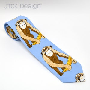 May include: A light blue necktie with a repeating pattern of brown monkeys holding yellow bananas. The text "JTCK Design" is printed on the tie.