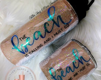 May include: Two glitter tumblers with the text "The Beach is Calling and I Must Go" in turquoise lettering. The tumblers are both a light brown color with a glittery finish.