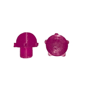 May include: Two magenta-coloured, 3D-printed objects. One is a rounded top with a threaded base, resembling a small knob. The other is a circular shape with five small protrusions around the edge. Both objects have a textured surface.
