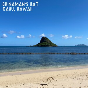 May include: A view of Chinaman's Hat, a small island off the coast of Oahu, Hawaii. The island is a popular tourist destination and is known for its unique shape, which resembles a hat.