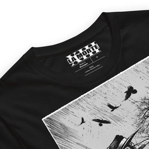 May include: Black t-shirt with a white graphic print of a person wearing a hat and crows flying in the sky. The shirt has a white tag that says "LA MORTE" and "Made in Nicaragua 100% combed ring spun cotton".