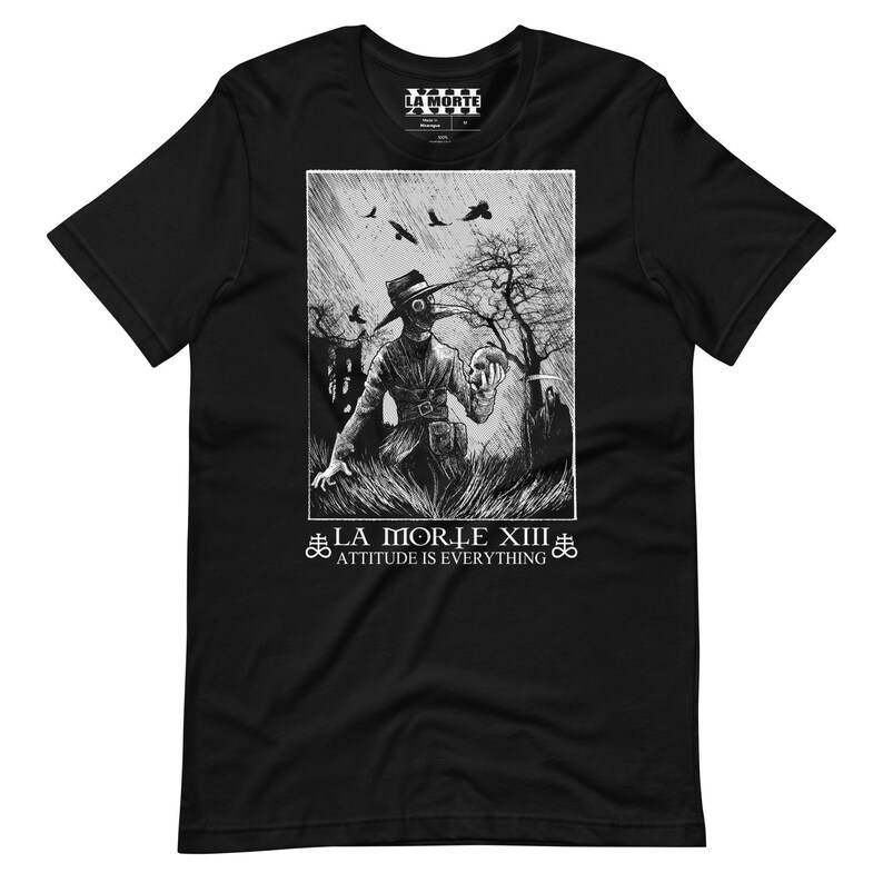 May include: Black and white graphic t-shirt featuring a hooded figure holding a skull in a graveyard setting. The text "La Morle XIII" and "Attitude is Everything" is printed below the image.