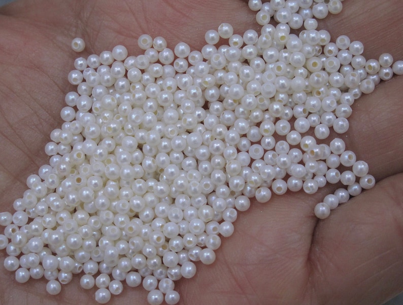 May include: A large pile of white pearl beads. The beads are round and have a smooth, glossy finish.