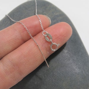 May include: A silver chain necklace with a lobster clasp closure. The chain is delicate and has a fine, cable-like design.