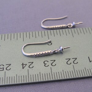 Pode incluir: Dois ganchos para brincos de prata com uma pequena p&eacute;rola transparente na ponta de cada gancho. Os ganchos medem aproximadamente 6,5 cm de comprimento e s&atilde;o medidos com uma r&eacute;gua.