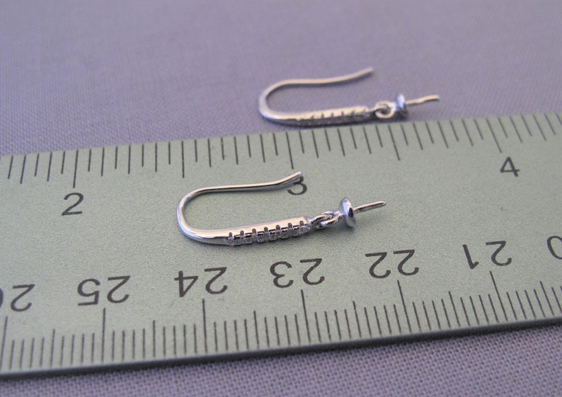 Pode incluir: Dois ganchos para brincos de prata com uma pequena p&eacute;rola transparente na ponta de cada gancho. Os ganchos medem aproximadamente 6,5 cm de comprimento e s&atilde;o medidos com uma r&eacute;gua.