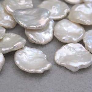 May include: A collection of white, irregularly shaped freshwater pearls. The pearls are smooth and have a slightly iridescent sheen.