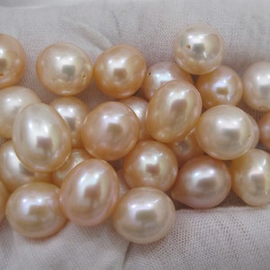 Puede incluir: Una colección de perlas de color rosa pálido de forma ovalada. Las perlas son lisas y lustrosas, con un ligero brillo iridiscente.