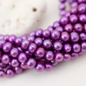 Peut inclure: Un brin de perles d'eau douce violettes. Les perles sont rondes et ont un grand lustre.