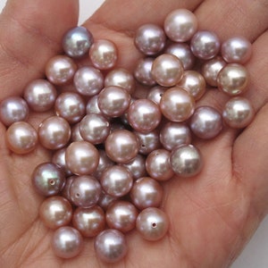 May include: A collection of round, iridescent pearls in shades of lavender, pink, and white. The pearls are smooth and have a subtle sheen.