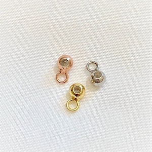 Puede incluir: Tres pequeñas cuentas de metal con bucles. Las cuentas son doradas, de oro rosa y plateadas.