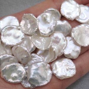 May include: A collection of white, irregular shaped, iridescent freshwater pearls. The pearls are smooth and have a natural, organic look.