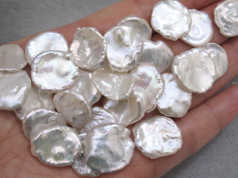 May include: A collection of white, irregular shaped, iridescent freshwater pearls. The pearls are smooth and have a natural, organic look.
