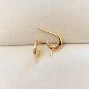 May include: Two gold-toned earring posts with a half-circle design. The posts are designed to be used with a variety of earring styles.