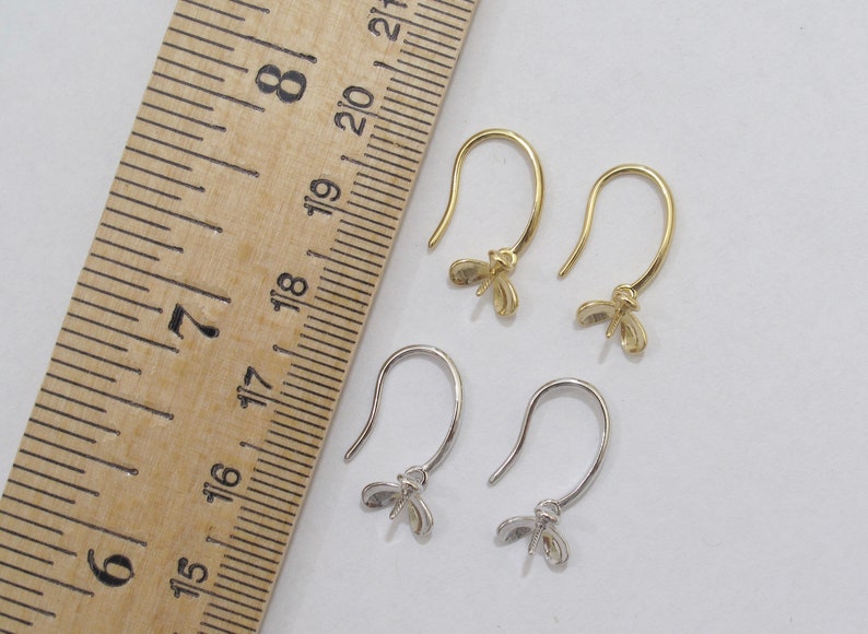 May include: Two pairs of earring hooks with a butterfly design. The hooks are made of metal and are available in gold and silver.