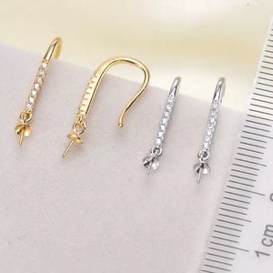 Pode incluir: Tr&ecirc;s pares de fechos de brincos com um design de cristal transparente. Os fechos s&atilde;o de cor dourada e prateada e medem aproximadamente 2,5 cm de comprimento.