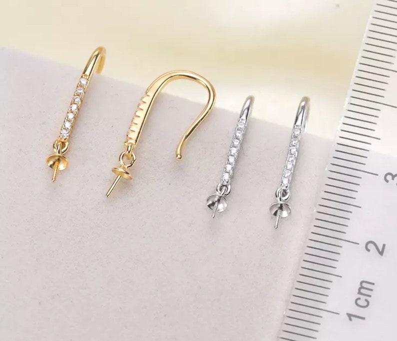 Pode incluir: Tr&ecirc;s pares de fechos de brincos com um design de cristal transparente. Os fechos s&atilde;o de cor dourada e prateada e medem aproximadamente 2,5 cm de comprimento.