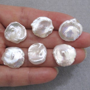 May include: Six white, round, irregular shaped freshwater pearls. The pearls have a smooth, iridescent surface.