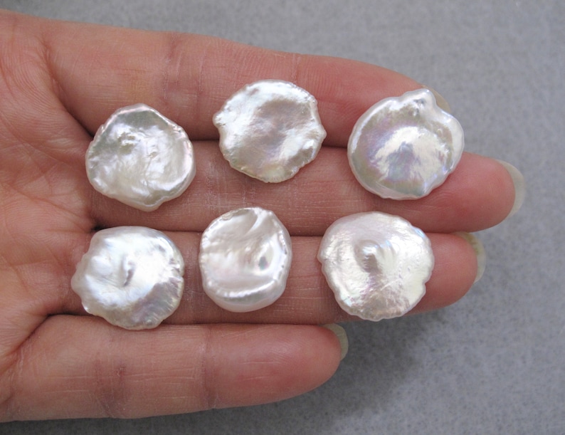 May include: Six white, round, irregular shaped freshwater pearls. The pearls have a smooth, iridescent surface.