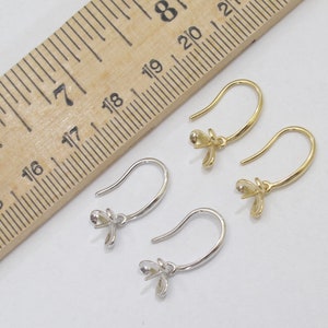 May include: Two pairs of earring hooks, one pair is gold and the other is silver. The hooks are approximately 1.75 inches long and have a small flower-shaped bail at the top.
