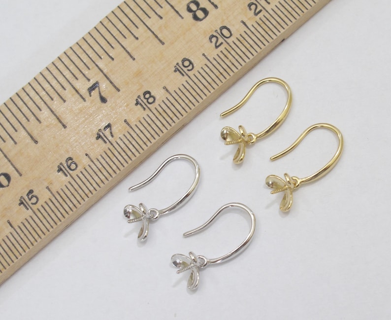May include: Two pairs of earring hooks, one pair is gold and the other is silver. The hooks are approximately 1.75 inches long and have a small flower-shaped bail at the top.