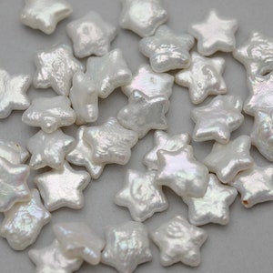 May include: A collection of white pearl star-shaped beads. The beads are iridescent and have a slightly irregular shape.