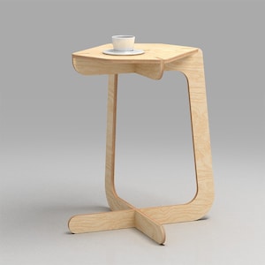 May include: A light wood side table with a curved base and a rounded top. A white cup and saucer are on the table.